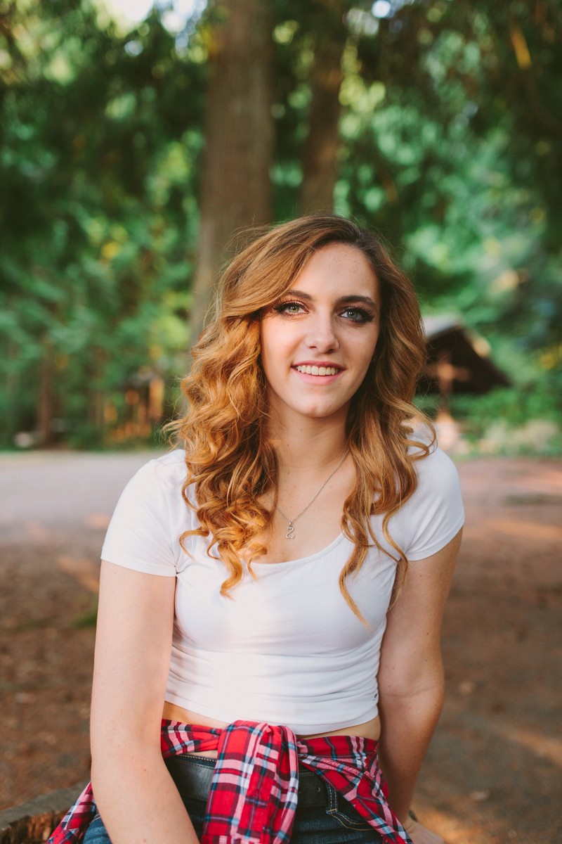 High school senior with a curled hairstyle, in casual clothes, at Scenic Beach State Park in Kitsap County, WA. 