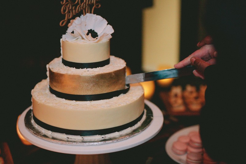 Two grooms cutting gold and black wedding cake. 