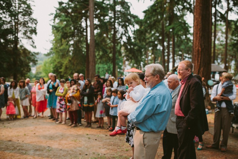 Groom's father holding granddaughter during wedding ceremony at Lincoln Park. 