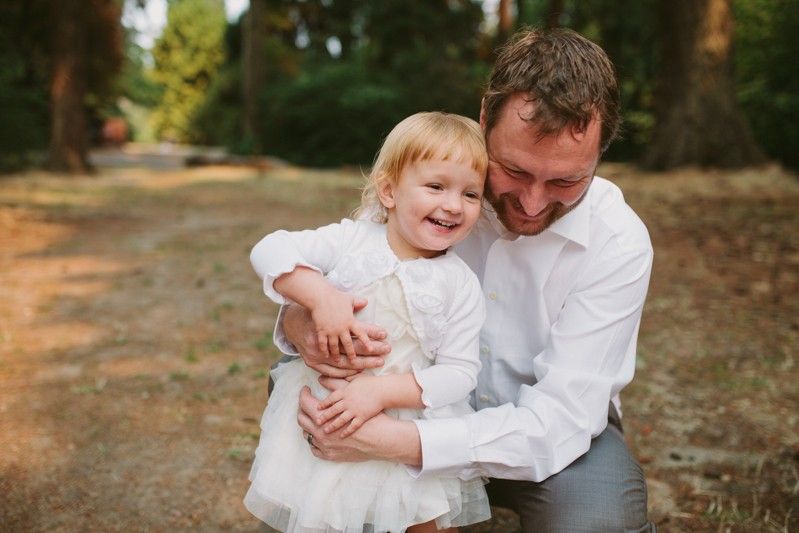 Groom playing with laughing daughter. 