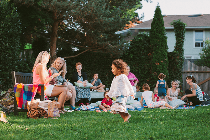 Guests mingling and children playing at an outdoor summer baby shower in Bremerton, WA. 