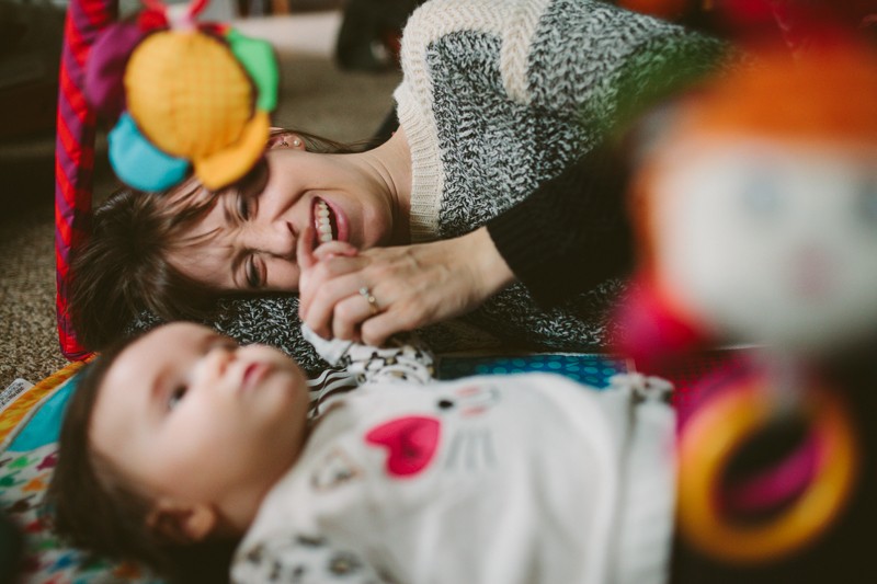 Young mom laughing at adorable baby girl during play time, at their home on Bainbridge Island. 
