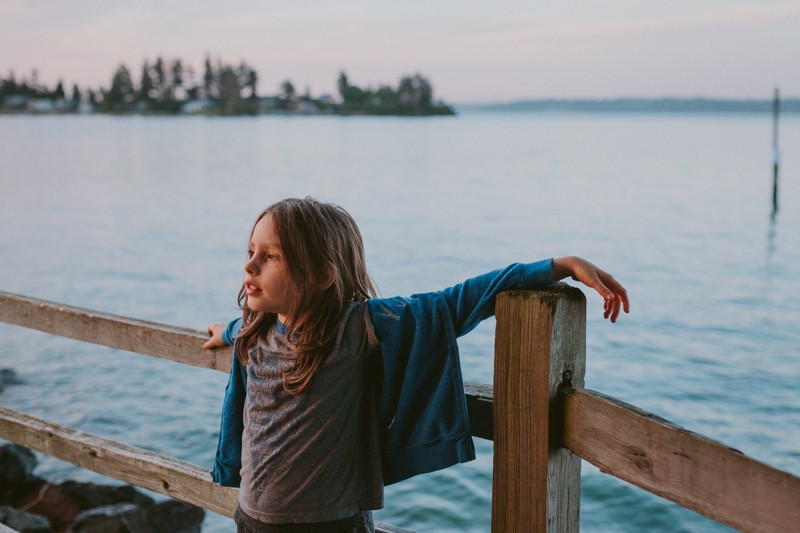 Pacific Northwest adventurer watches the sun set, near the water, on Bainbridge Island, WA.