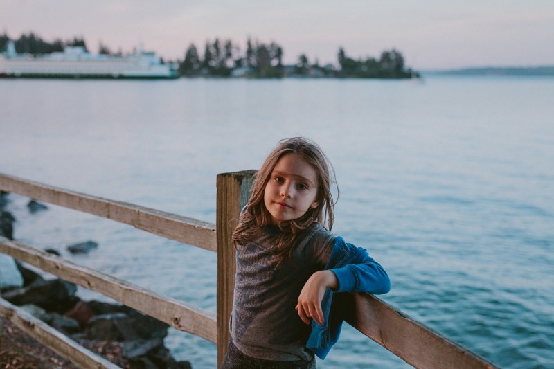 Boy with long hair and ferry boat in the water, on Bainbridge Island.