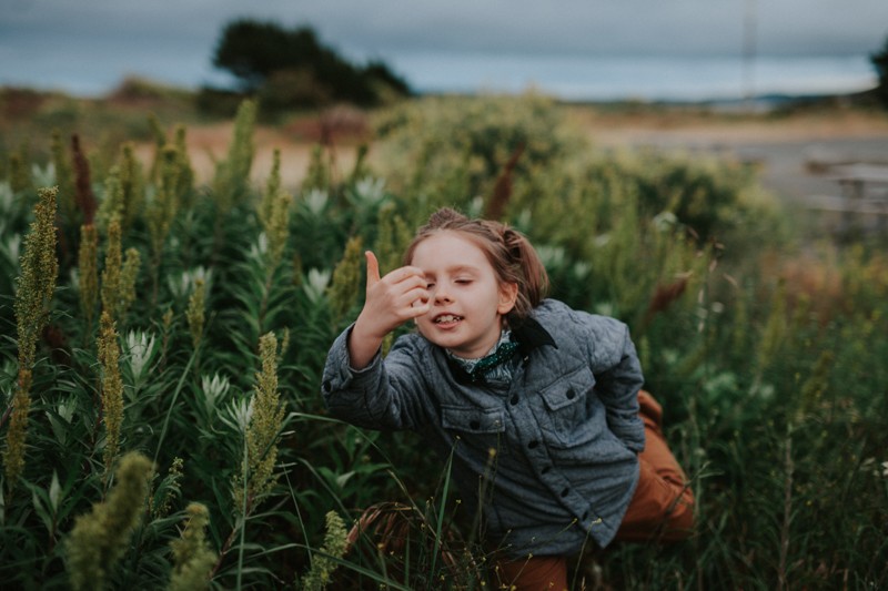 Little boy playing in tall plants at the beach in Port Townsend, WA.