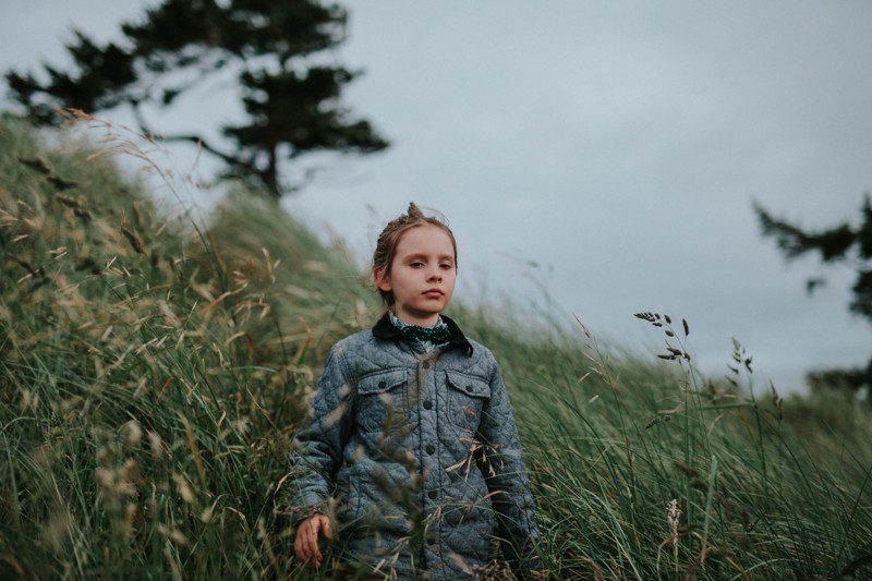 Little boy walking through long beach grass at Fort Worden Park in Port Townsend, WA.
