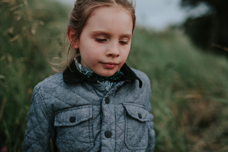 Boy wearing a polka dot bow tie walks through long grass in Port Townsend, WA.