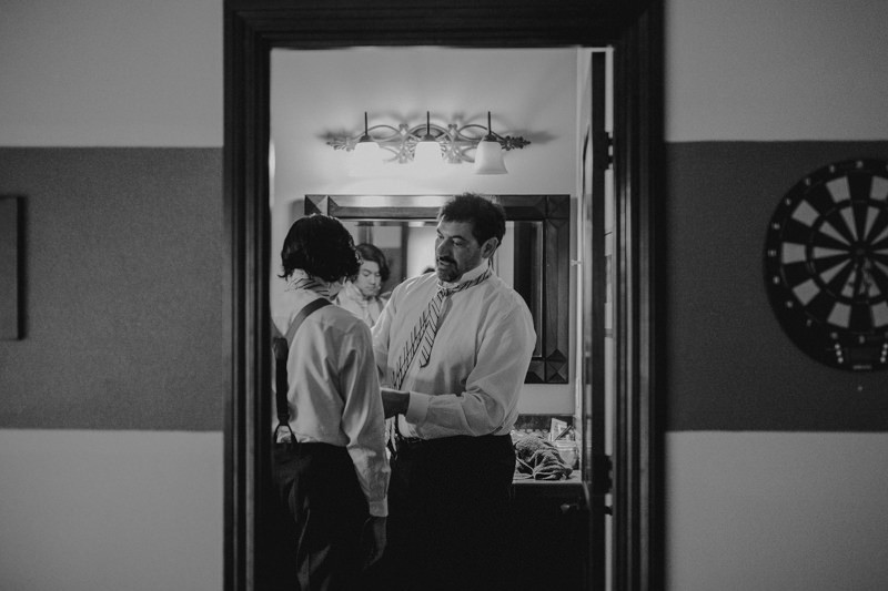 Groom helping his teenage son and groomsman get ready.