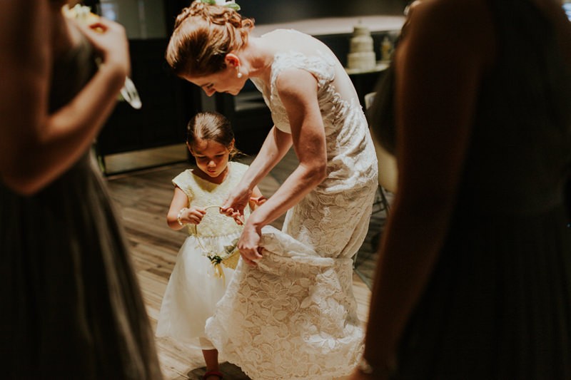 Bride helps flower girl with her basket.