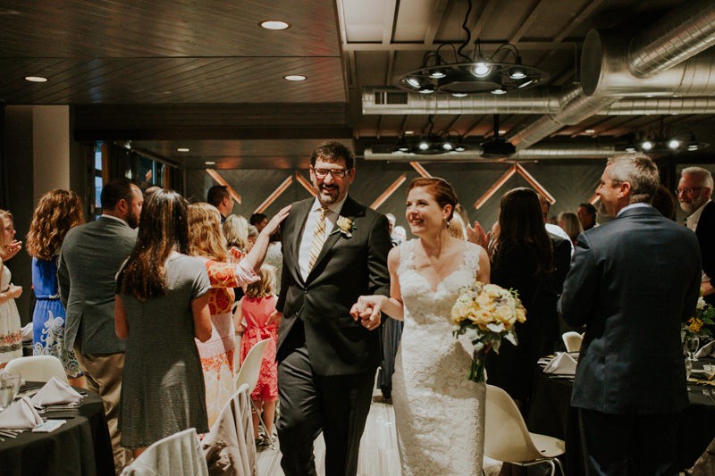 Newly married bride and groom smile at guests.