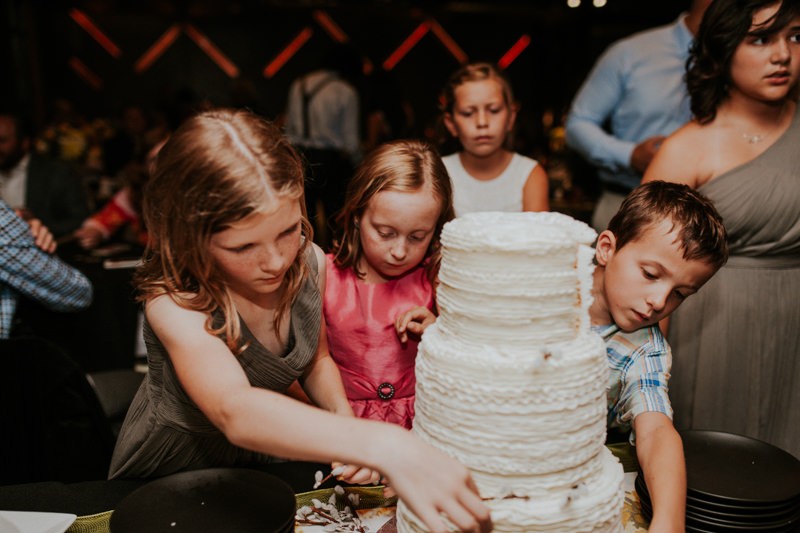Kids eagerly help with cutting the cake for guests.