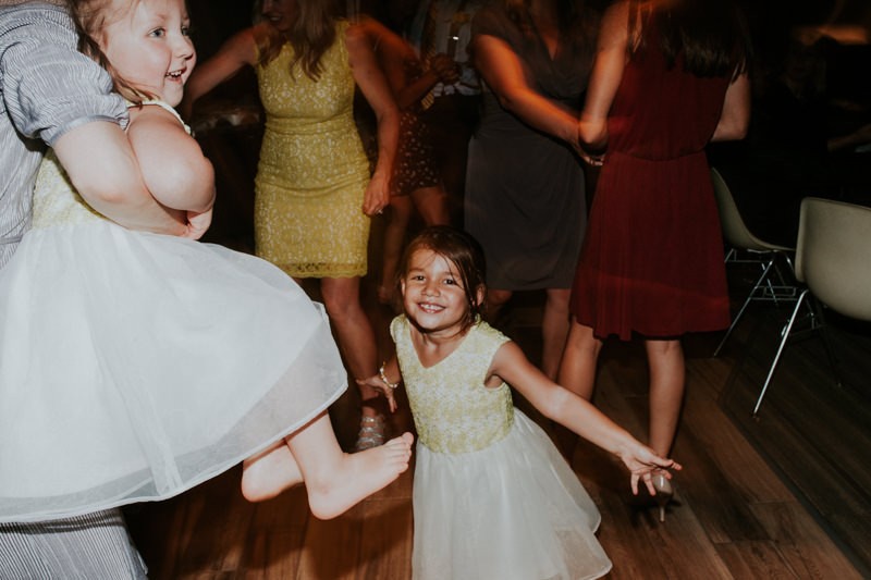 Flower girls having a blast dancing during an indoor wedding reception.